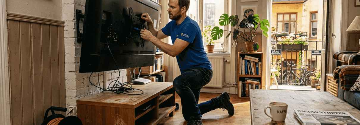 En fackman kommer hem och sätter upp tv:n på väggen.