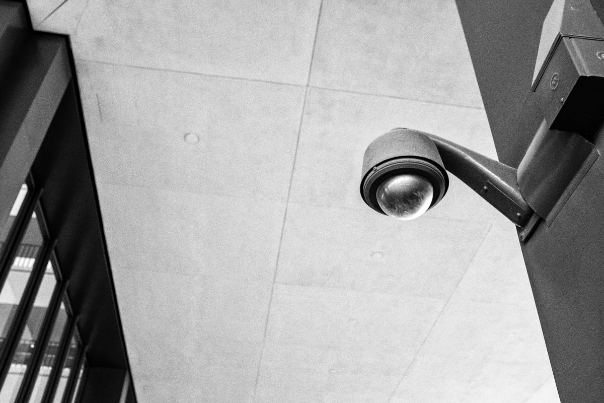 Övervakningskamera monterad på vägg mot ljus himmel