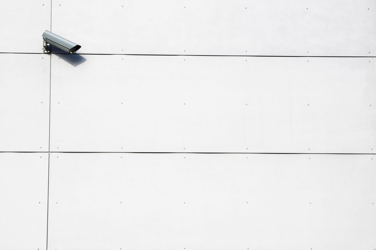Övervakningskamera monterad på vägg mot ljus himmel