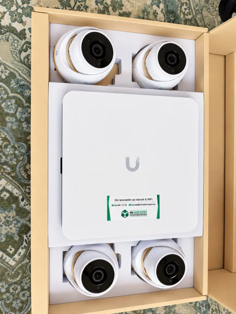 UniFi NVR Instant och fyra G5 Turret Ultra-kameror i kartongen före installationen, med Min Datorsupports dekal på inspelaren