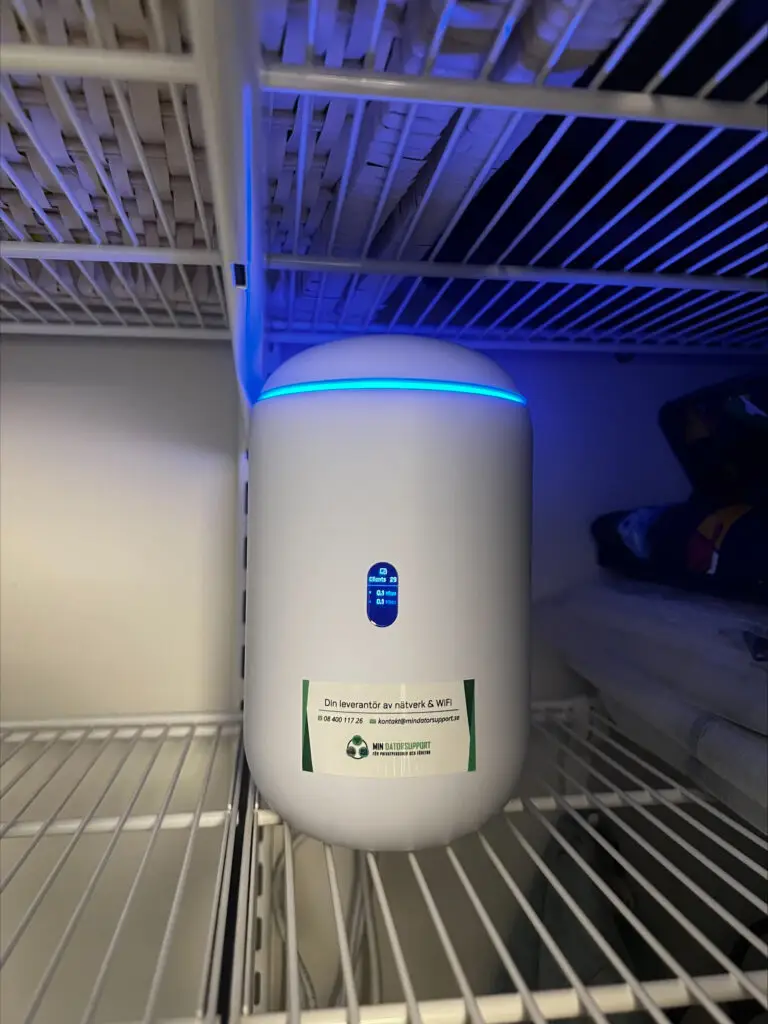 UniFi Dream Router 7 på en hylla i garderoben, displayen visar 29 uppkopplade enheter