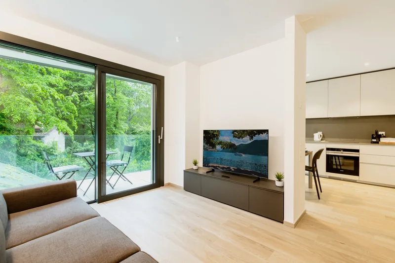 Ljust vardagsrum med tv på tv-bänk och parkettgolv